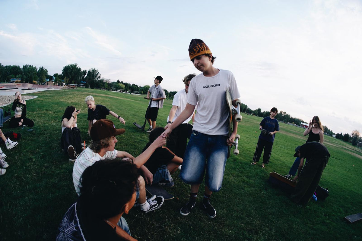 SkateLife Idaho leader fist-bumping a young skater on a park lawn