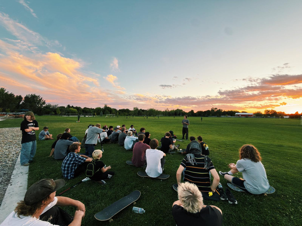 SkateLife Idaho skaters gathered on a park lawn at sunset